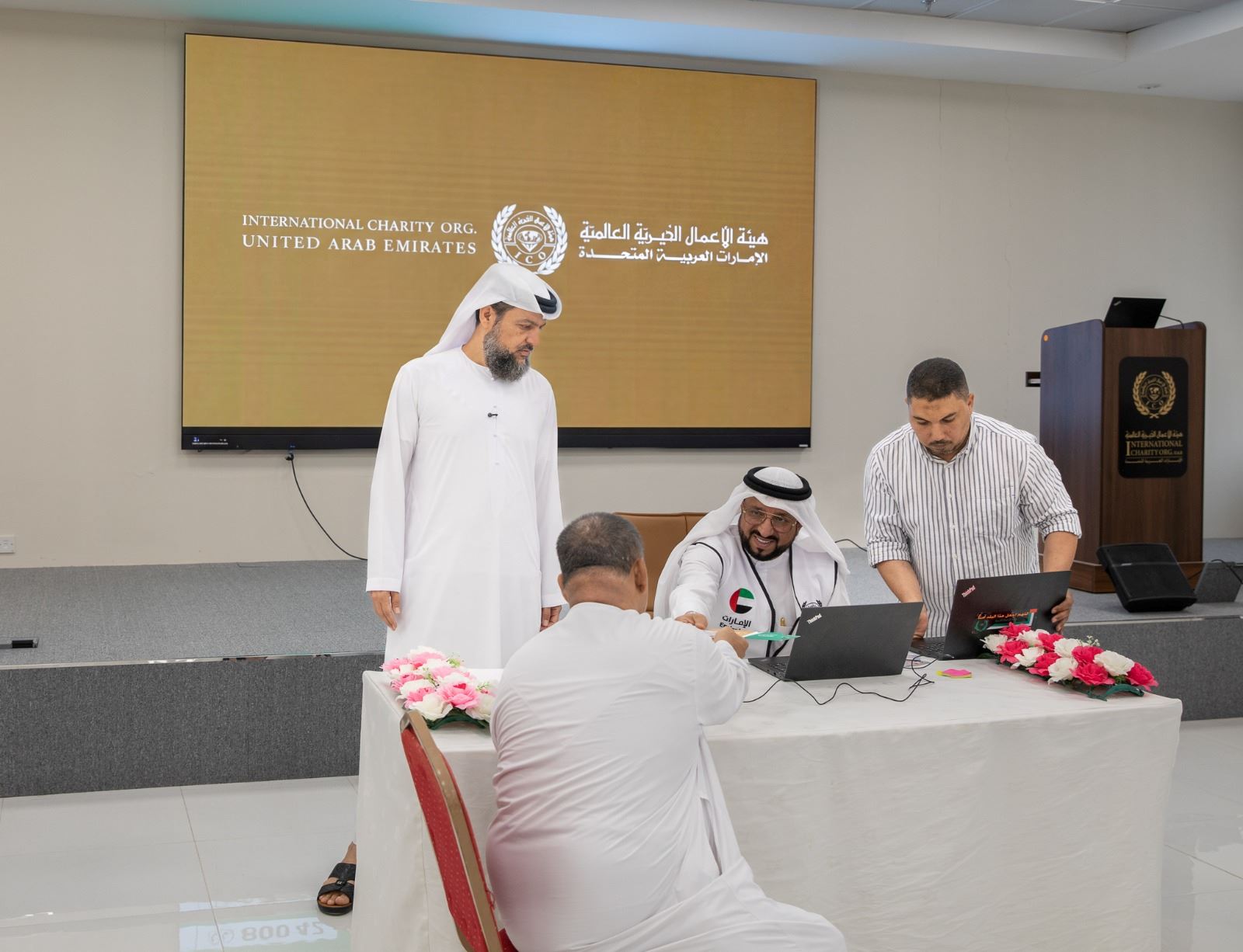 Officials from the International Charity Organization UAE assisting a beneficiary during a project implementation meeting in the United Arab Emirates.